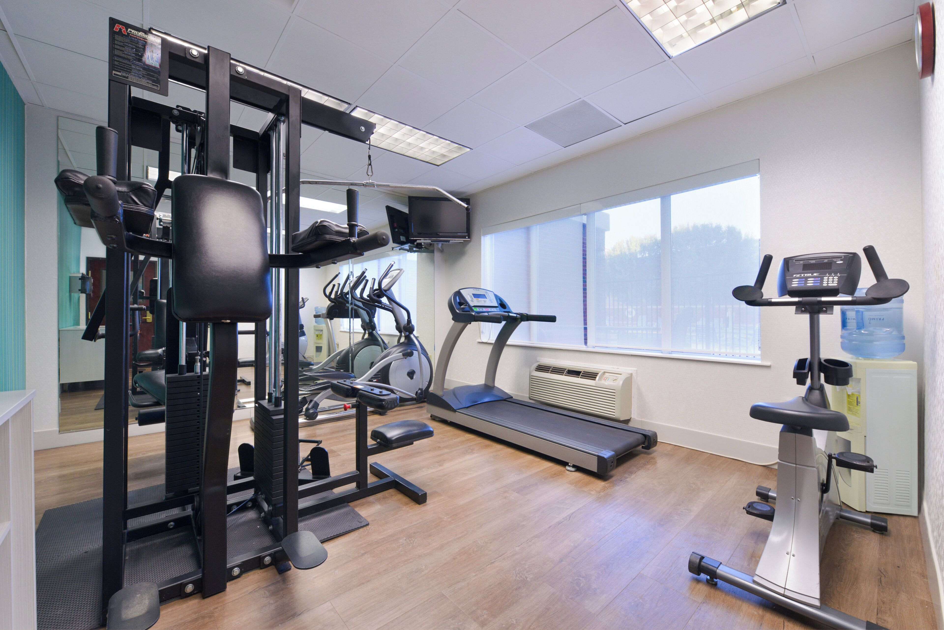 Ett gym med olika typer av träningsutrustning, inklusive löpband, crosstrainer och styrketräningsmaskiner.