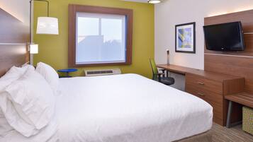 A hotel room with a large bed, a desk, a chair, a television, and a window with a view.