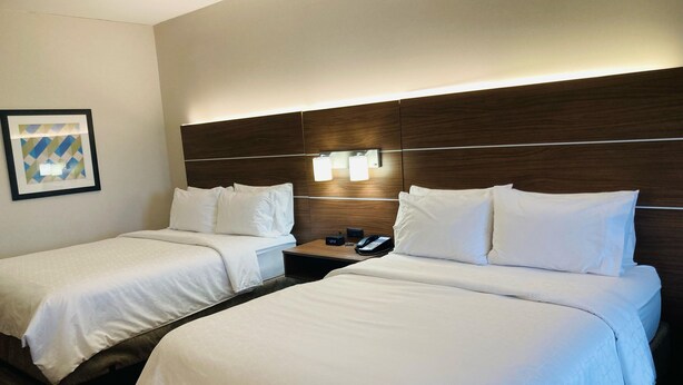 A hotel room with two beds, a nightstand with a phone, and a wall-mounted light fixture. - Holiday Inn Express & Suites Abilene by IHG (Abilene)
