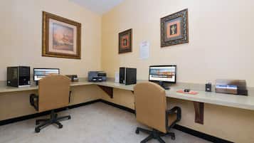 A conference room with two office chairs, a long table, and three desktop computers.