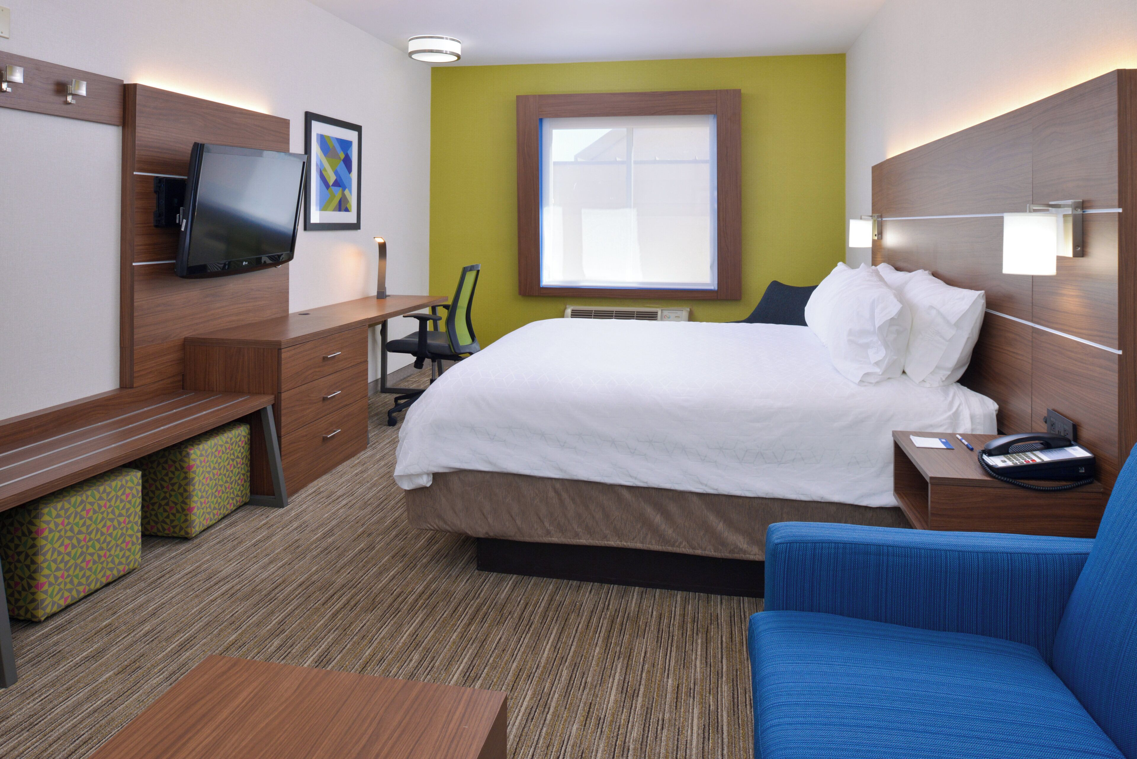 Una habitación de hotel con una cama, un escritorio, una silla, un televisor y una ventana.