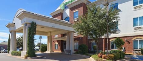 A Holiday Inn Express hotel with a covered entrance, a brick facade, and a landscaped front yard.