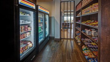 Un pasillo de un supermercado con secciones refrigeradas a la izquierda y estantes llenos de aperitivos y bebidas a la derecha.