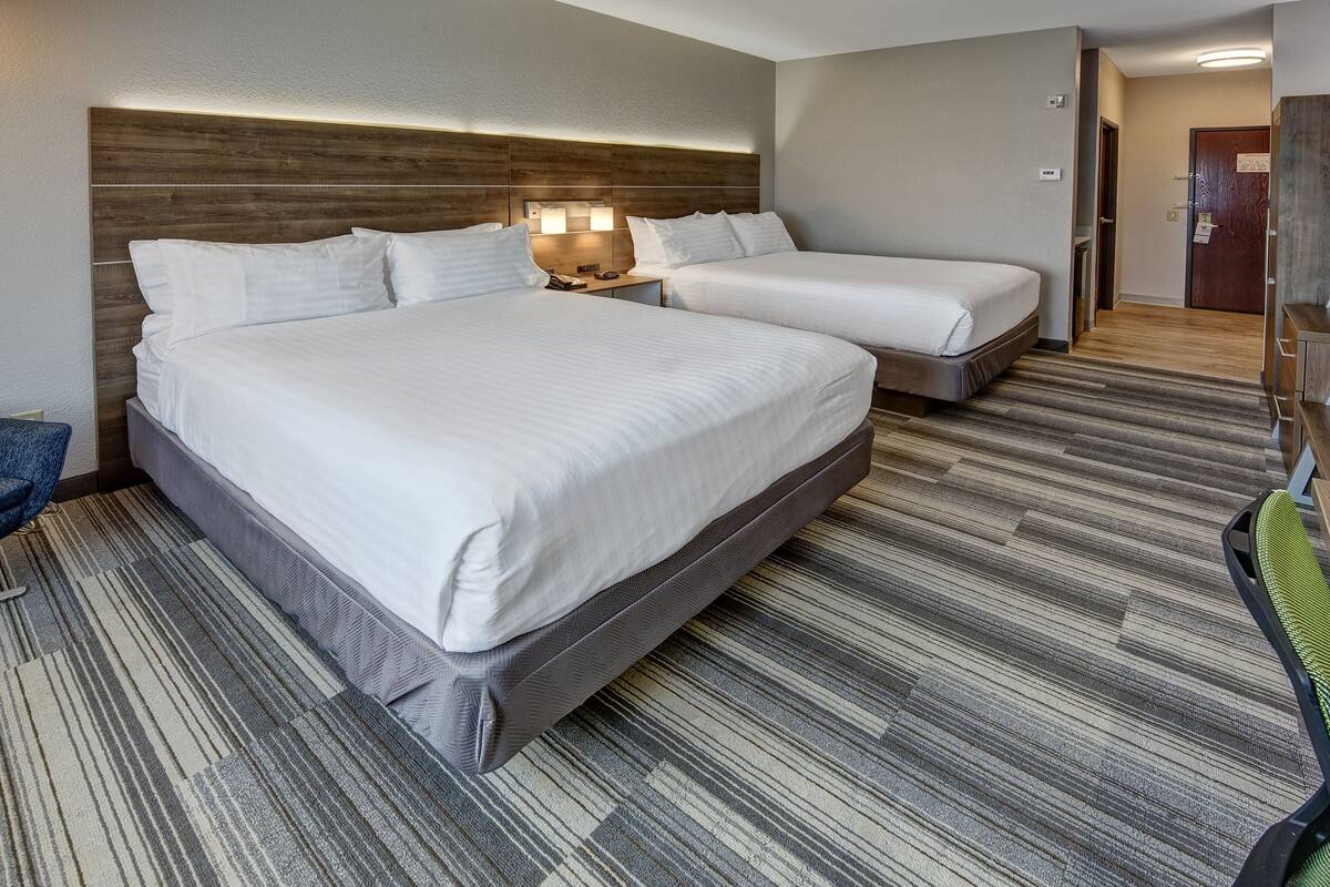 A hotel room with two beds, a desk, and a chair.