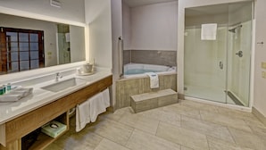 Ein modernes Badezimmer mit großem Spiegel, zwei Waschbecken, einer Badewanne und einer begehbaren Dusche.