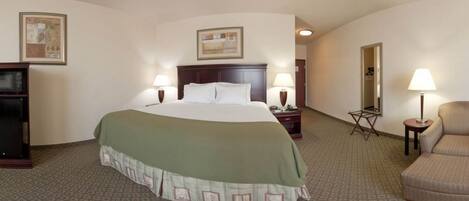 A hotel room with a large bed, two bedside tables with lamps, a chair, a desk with a lamp, and a television.