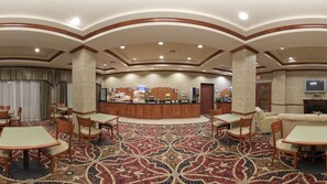 Un hall d’hôtel doté d’un comptoir d’accueil central, de plusieurs espaces aménagés avec des sièges et d’un tapis à motifs.