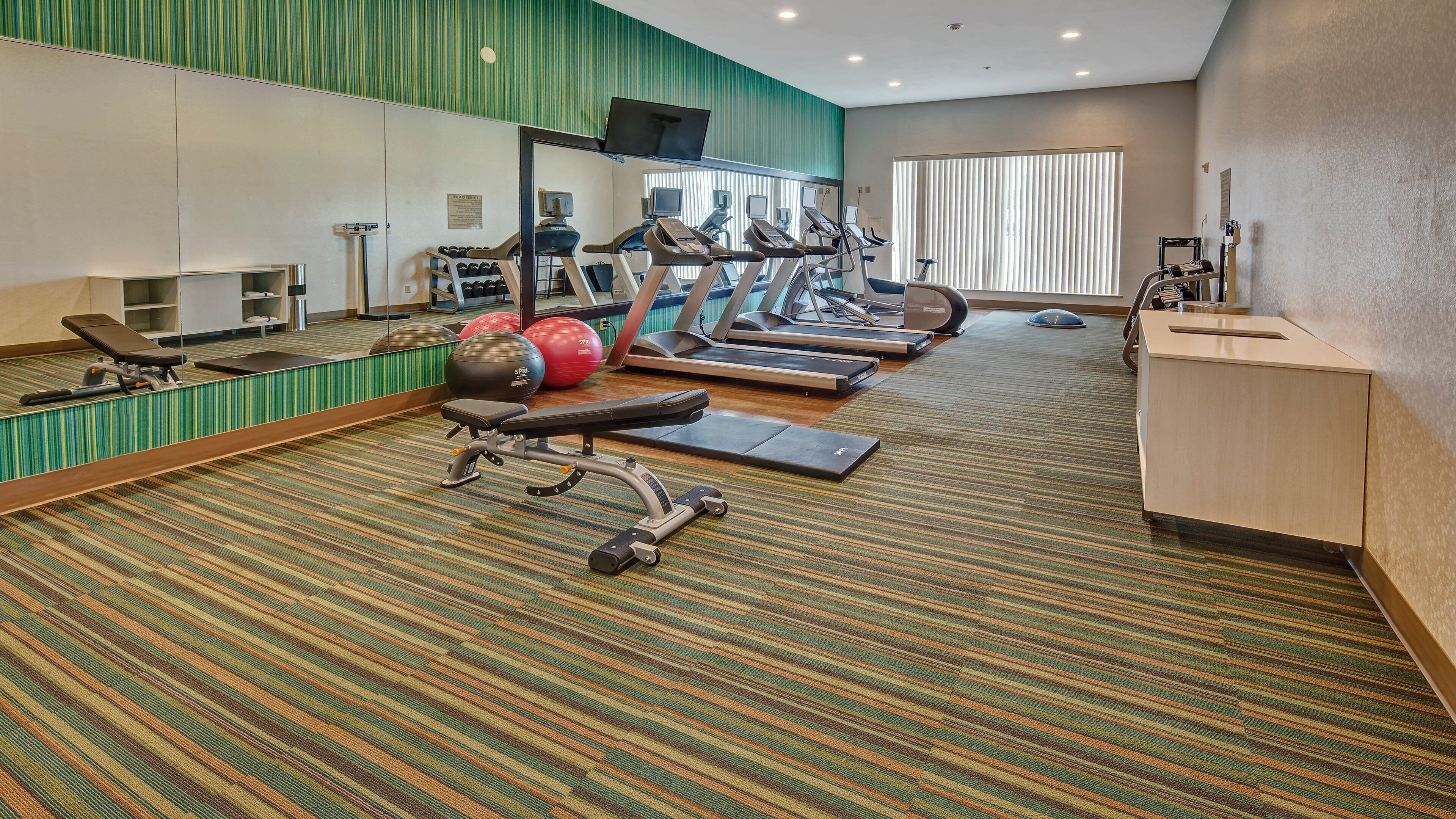 A hotel fitness center with treadmills, elliptical machines, and free weights.