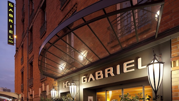 A hotel named 'Gabriel' with a brick facade, large windows, and a covered entrance area. - Hôtel Gabriel Issy (Issy-les-Moulineaux)