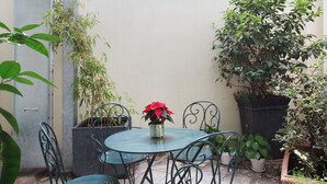 A small outdoor patio with a round table and chairs, surrounded by potted plants and a metal fence. - Hôtel Gabriel Issy (Issy-les-Moulineaux)
