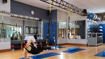 Ein Fitnessraum mit blauen Matten, einer Hängesystem-Kabelzuganlage und Trainingsgeräten.