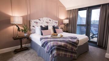 A bedroom with a large bed, two bedside tables, a chandelier, and a view of the outside.