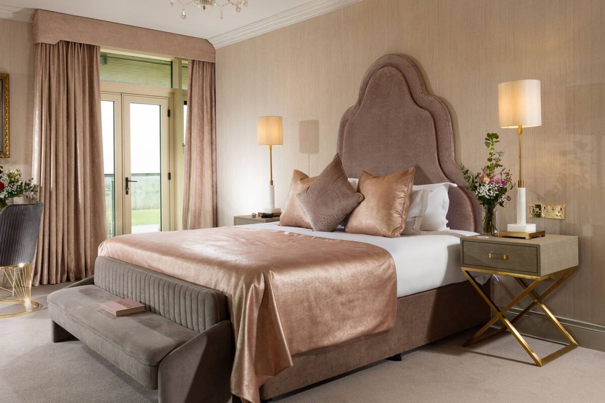 A large bed with a headboard, bedside tables, and a bench.