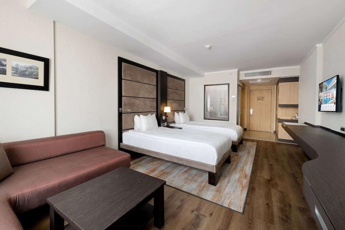 Ein Hotelzimmer mit Bett, Sofa, Schreibtisch und Fernseher.