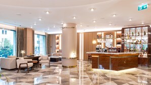 Un hall d’hôtel moderne doté d’un bar, d’espaces aménagés avec des sièges et d’une grande colonne.