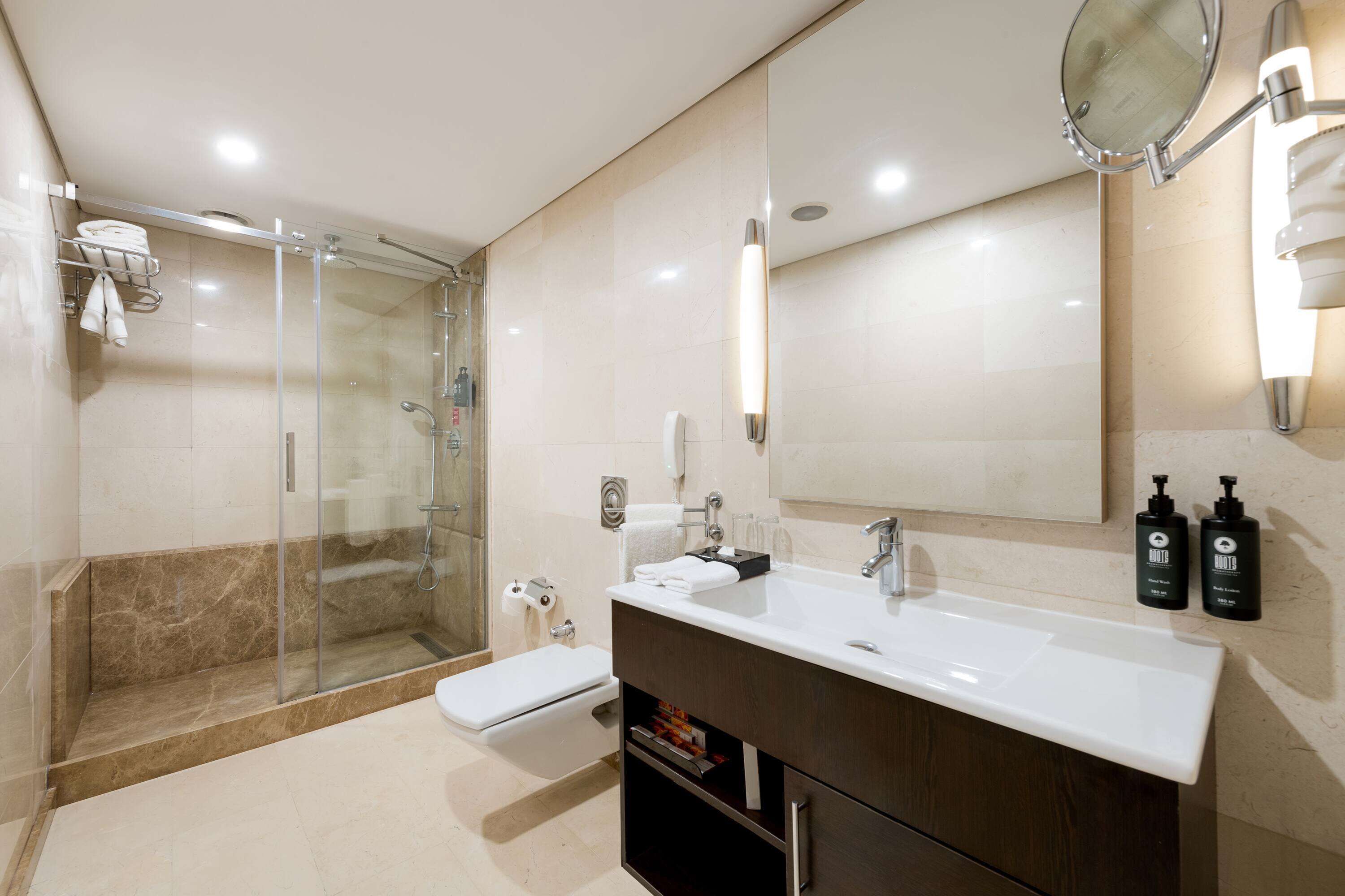 A modern bathroom with a glass-enclosed shower, a white sink, and a large mirror.