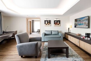 A modern living room with a sofa, armchair, and coffee table, a wooden cabinet, and artwork on the wall.