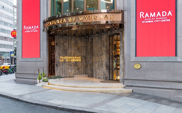 Der Eingang des Ramada Plaza by Wyndham in Istanbul, mit einer Marmorfassade und beleuchteter Beschilderung.