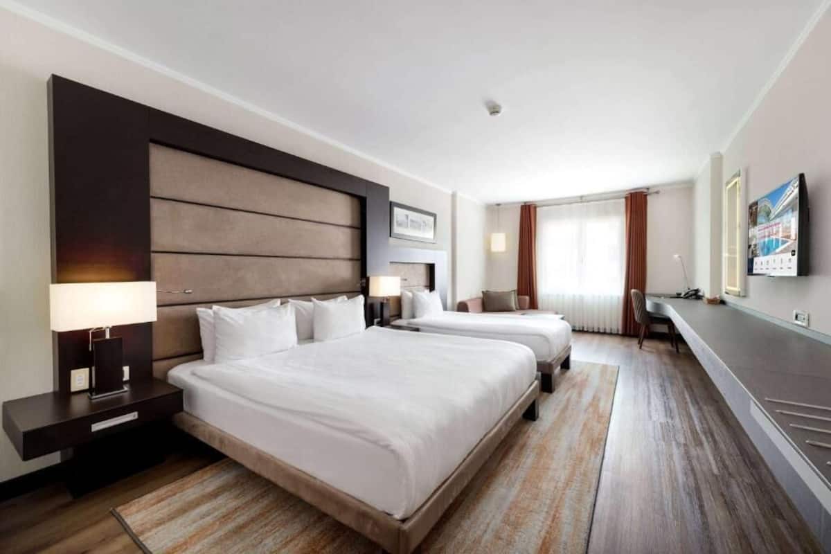 Ein Hotelzimmer mit zwei Betten, einem Schreibtisch und einem Fernseher.