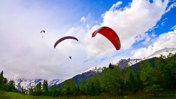 Un paisaje montañoso con varios parapentistas volando en el cielo.