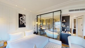 A hotel room with a large bed, a glass-enclosed bathroom with a bathtub, and a view of the city. - Radisson Hotel Shimla (Shimla)