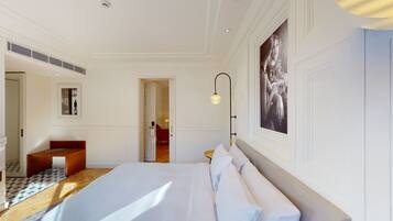 A hotel room with a large bed, a wooden bench, a framed picture, and a modern light fixture.