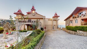 A building with a central entrance, a statue, and a cobblestone path leading to a gated area.