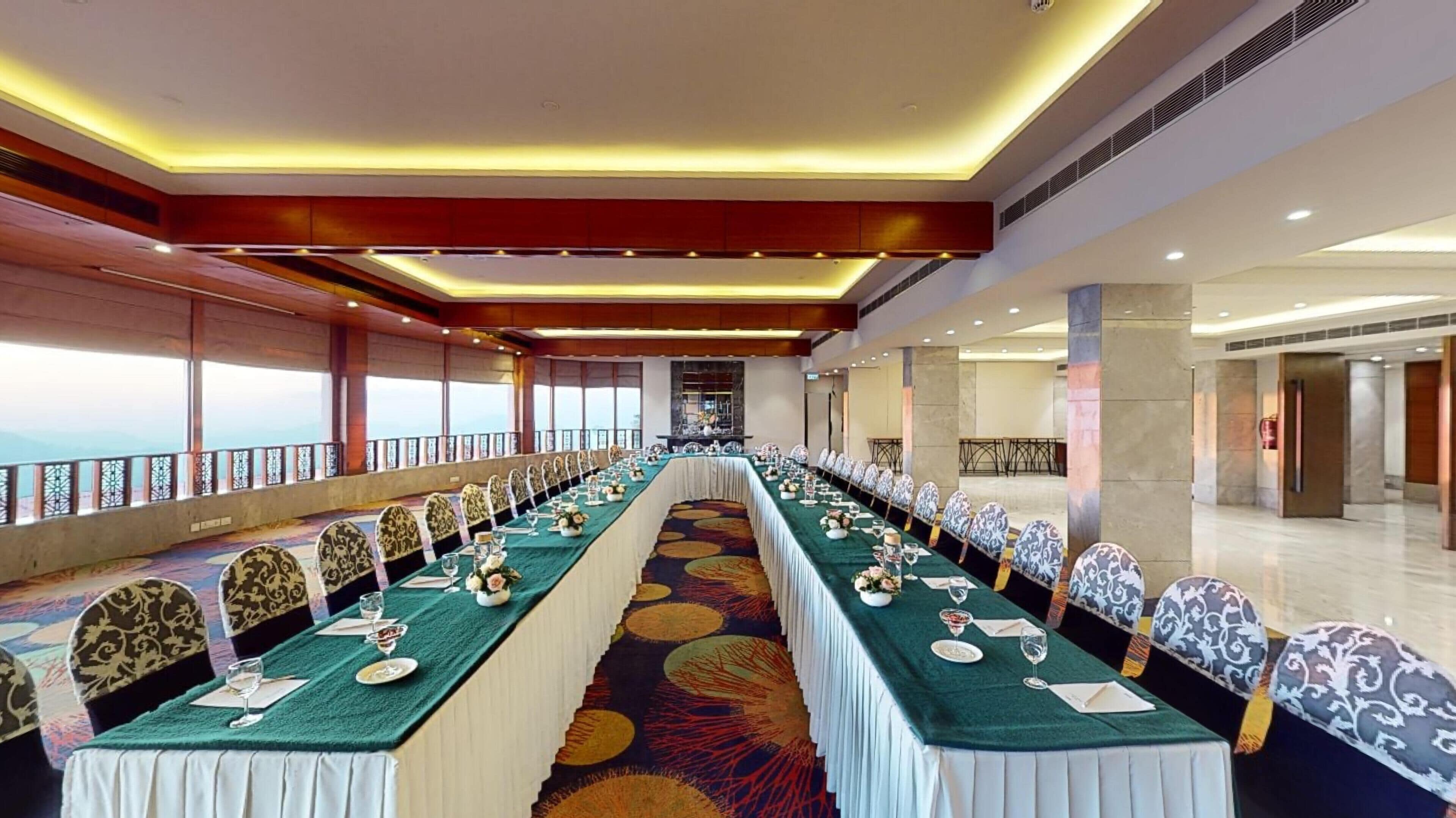 A conference room with a long table, chairs, and a view of the mountains.