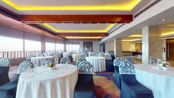 Un salón de banquetes con mesas redondas, sillas estampadas y vistas al exterior.