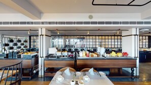 A modern restaurant with a long counter, multiple seating options, and a kitchen visible in the background. - Radisson Hotel Shimla (Shimla)