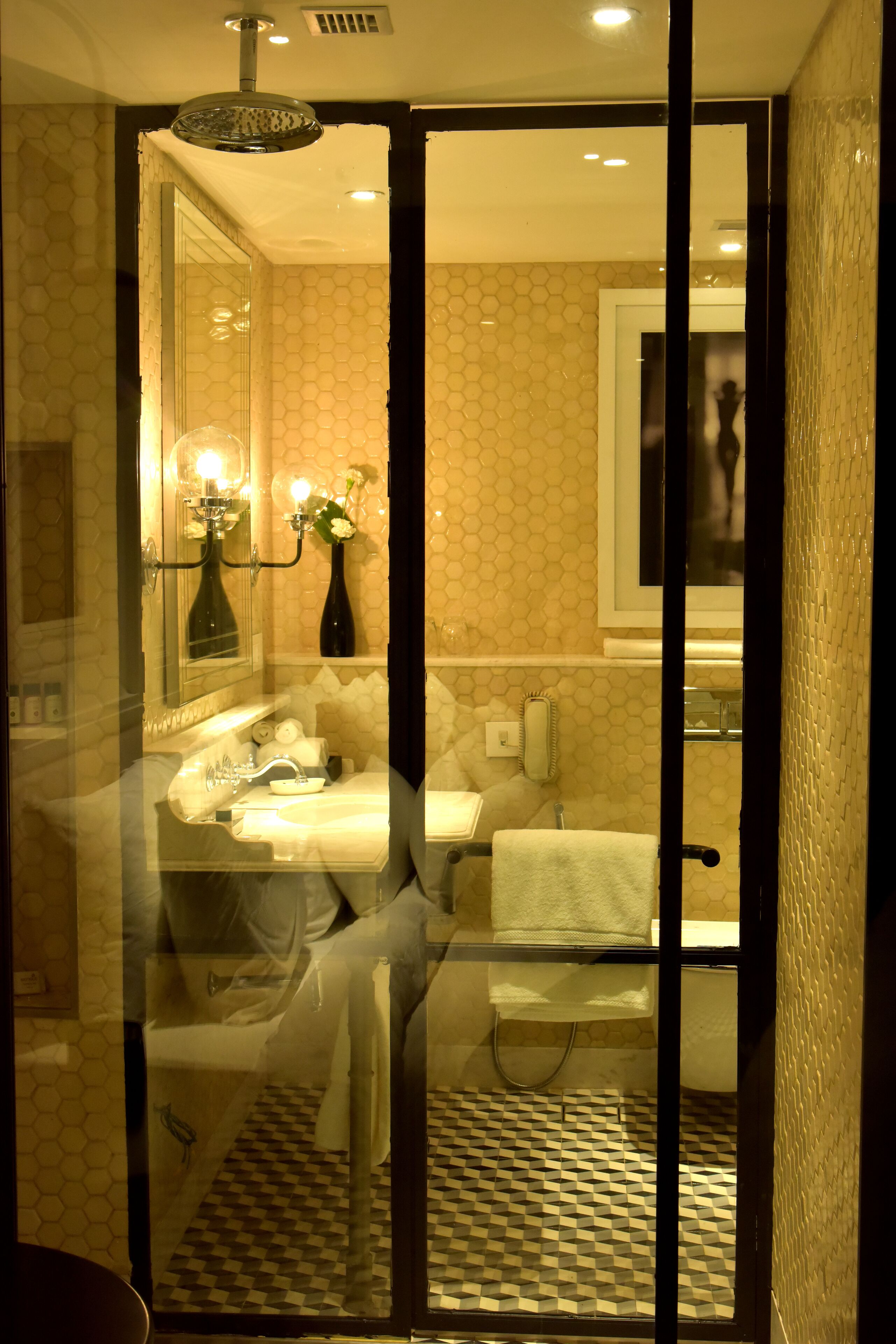 Une salle de bain avec une paroi en verre, un lavabo, un miroir, un porte-serviettes et un espace douche.