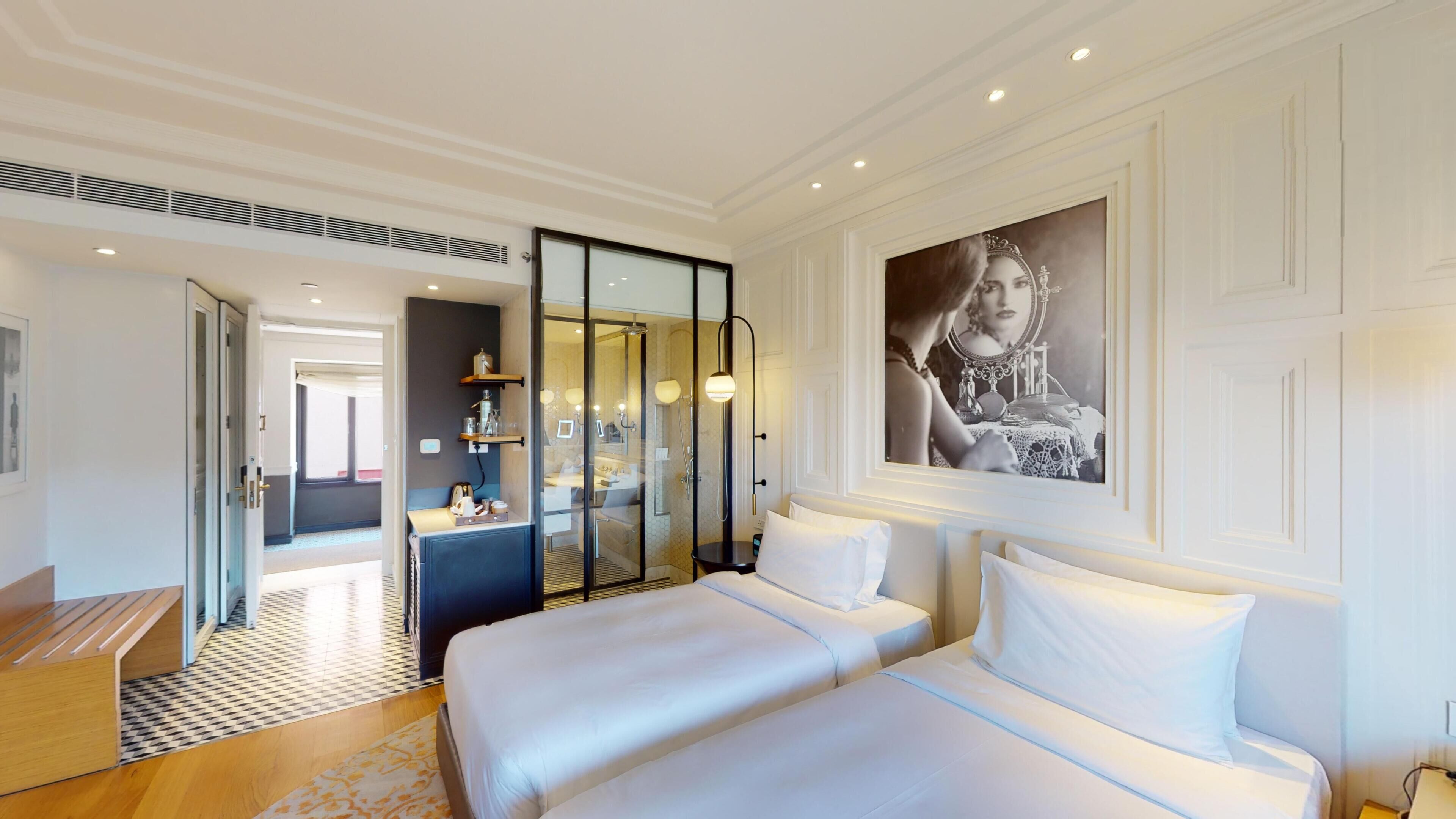 Habitación de hotel con una cama grande, zona de estar, ducha y baño.