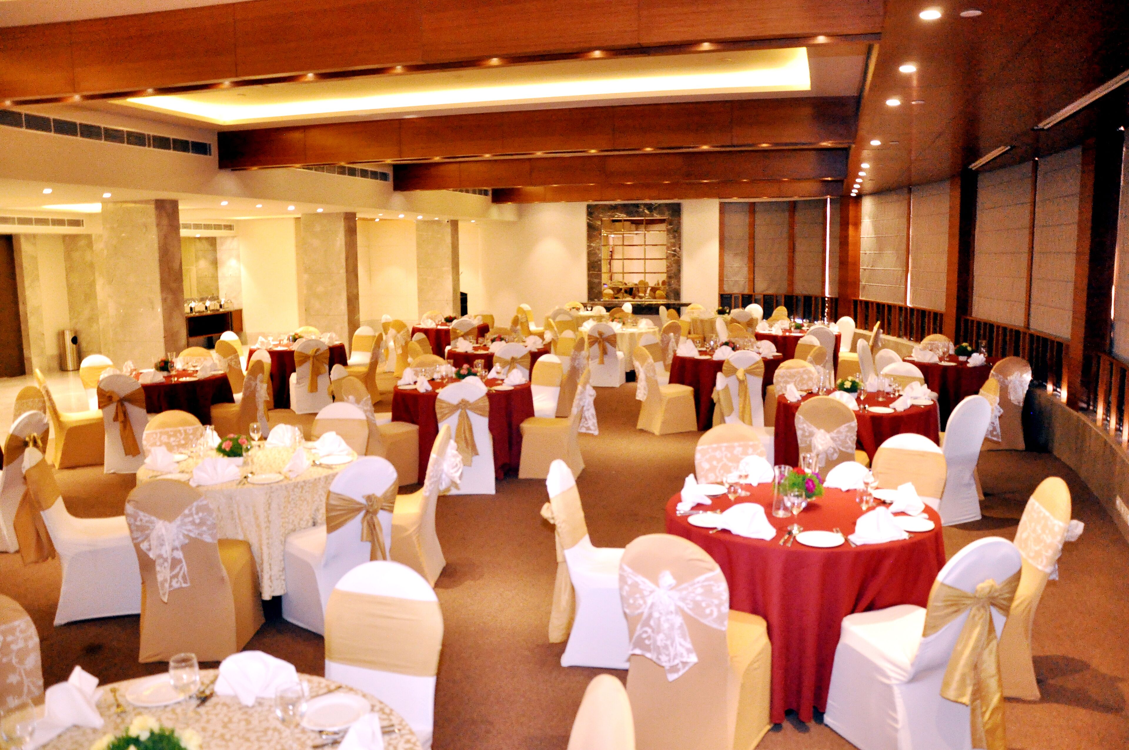 A banquet hall with round tables and chairs, each set with white tablecloths and gold sashes.