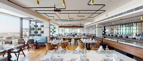 Un restaurante moderno con techos altos, conductos expuestos y una variedad de asientos, incluyendo mesas y cabinas.