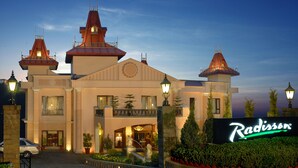 A hotel with a central tower and two smaller towers, a well-lit entrance, and a sign reading "Radisson".