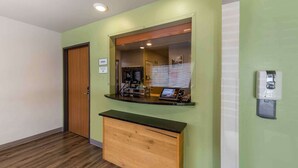 Una recepción con un mostrador de madera, un televisor y un interfono en la pared.