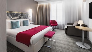 A hotel room with a large bed, a red chair, a sofa, and a small table. - East Side Hotel Paris Gare de l’Est, a member of Radisson Individuals (Paris)