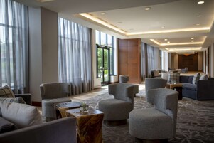 Eine geräumige Hotelhalle mit mehreren Sitzbereichen, großen Fenstern und einem modernen Deckenstil.