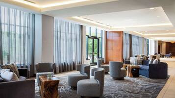 A spacious lobby with modern furniture, large windows, and a patterned carpet.