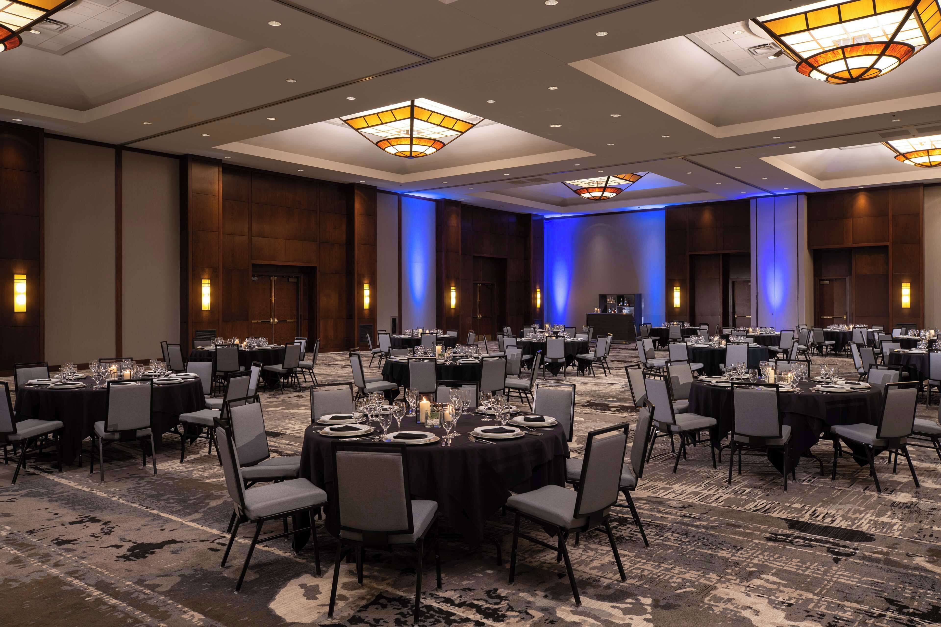 A large conference room with round tables, chairs, and a carpeted floor.