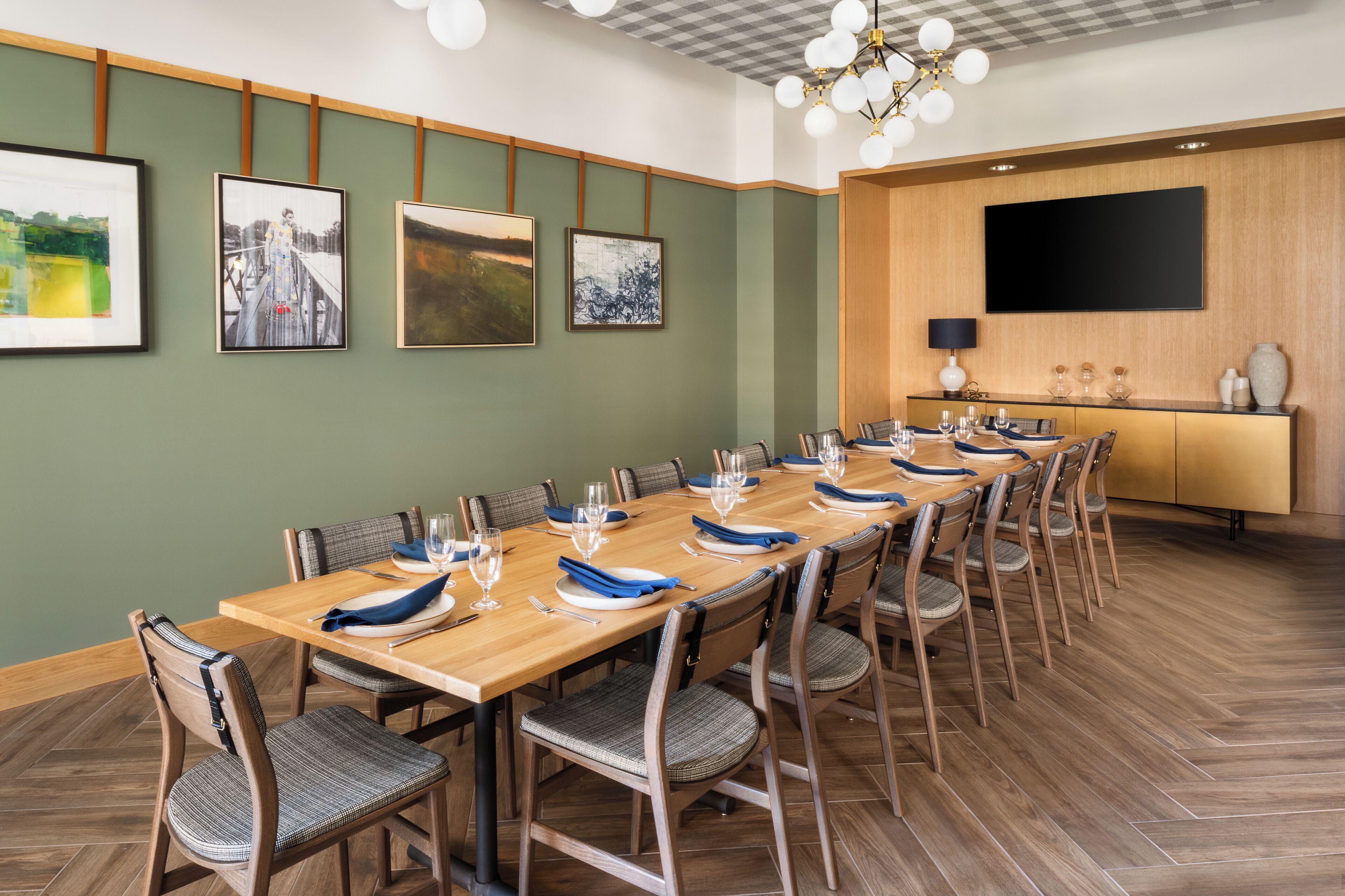 Une salle de conférence avec une longue table en bois, des chaises et un téléviseur à écran plat fixé au mur.