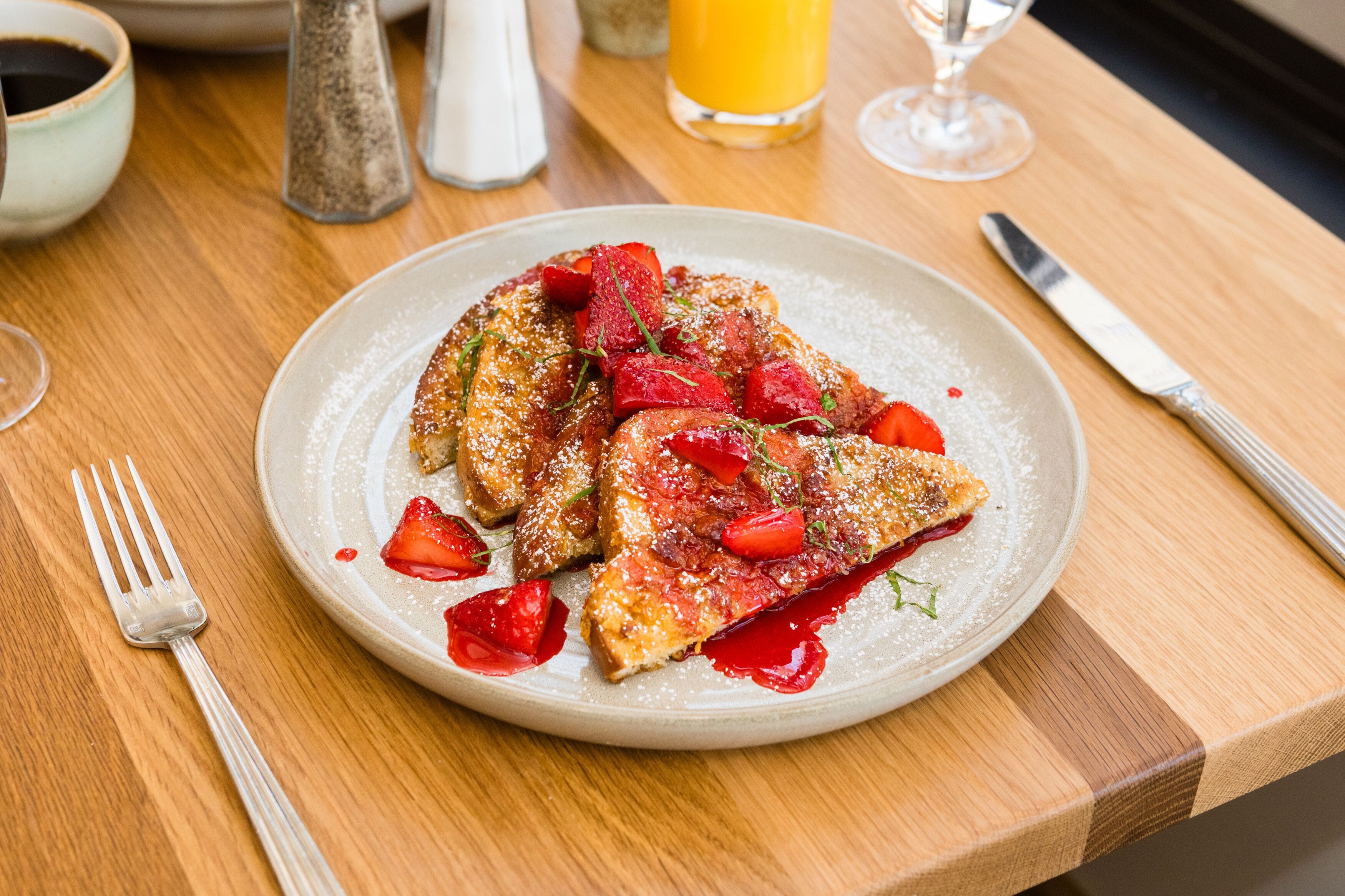 A plate of food on a wooden table with a fork and knife beside it.