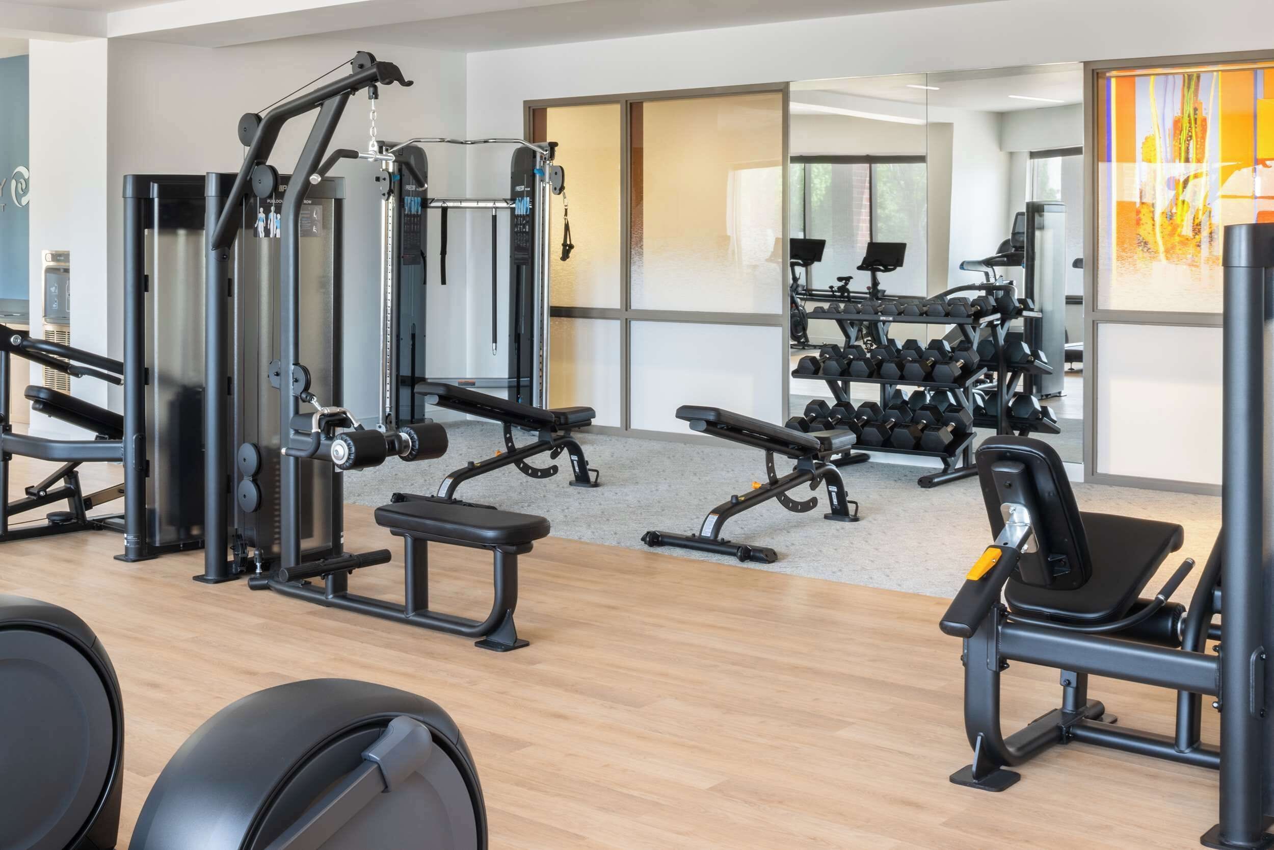 A gym with various exercise equipment, including weight machines, benches, and dumbbells.