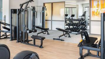 A gym with various exercise equipment, including weight machines, benches, and dumbbells.