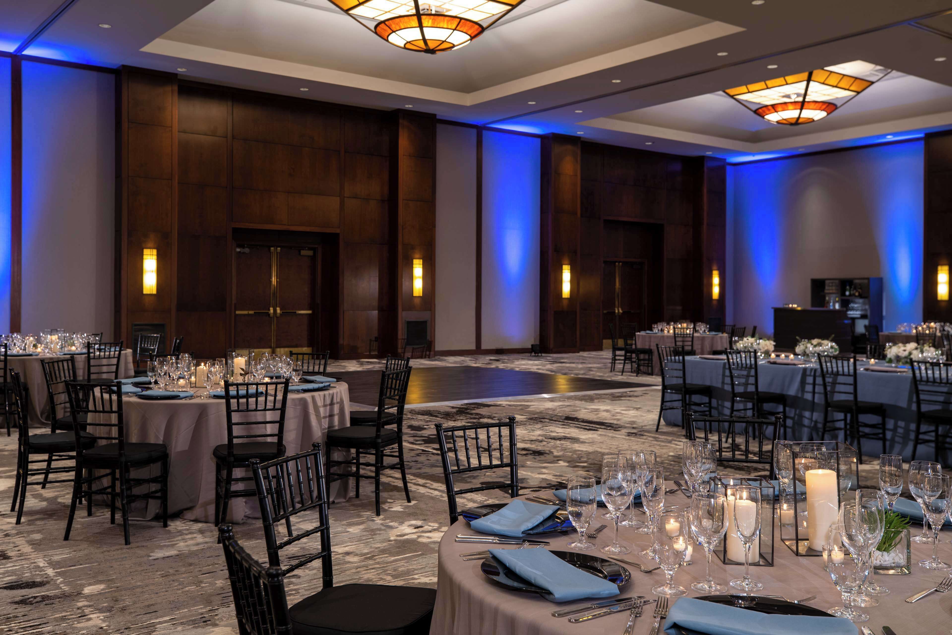 A banquet hall with round tables set for dining, equipped with candles and table settings.