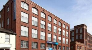 Un bâtiment en briques rouges, doté de nombreuses fenêtres et d’une enseigne indiquant « Travelodge ».