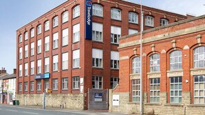 Un bâtiment en briques rouges, doté de nombreuses fenêtres et d’une enseigne « Travelodge ».