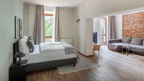Un dormitorio moderno con cama, televisor, sofá y pared de ladrillo.