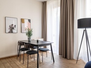 Ein moderner Essbereich mit Tisch, Stühlen, einer Zimmerpflanze und Bildern an der Wand.