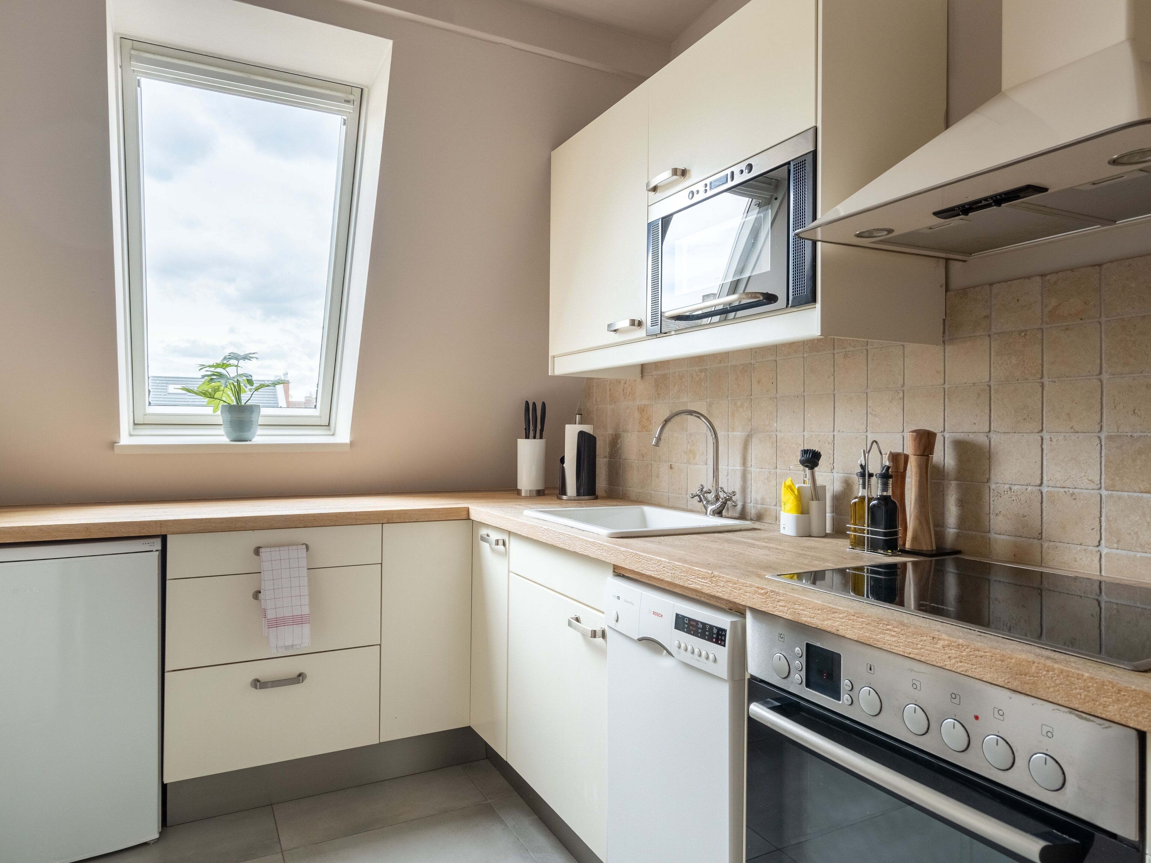 A modern kitchen with white cabinets, a Bosch dishwasher, a microwave, and an oven.